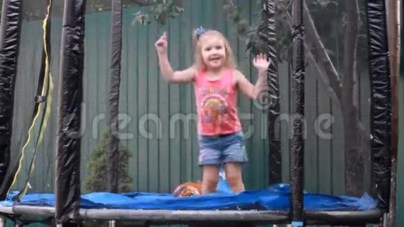 小女孩在蹦床上跳在乡下的房子里玩儿童游戏视频的预览图