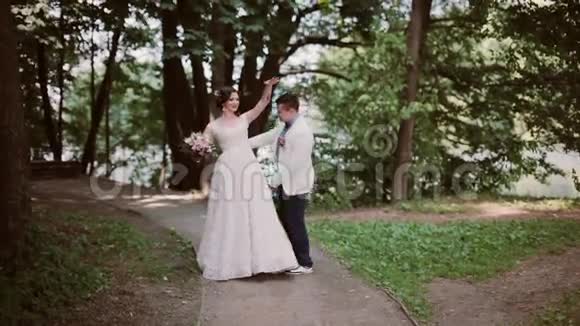 公园里的时髦新娘和新郎新郎把新娘抱在怀里绕来绕去快乐的恋人分享婚礼日视频的预览图