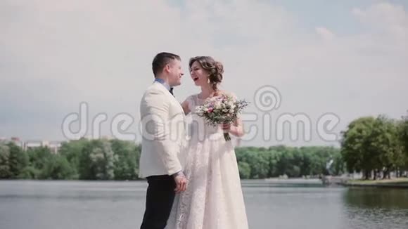 新婚之日一对相爱的情侣站在河岸上开心地笑着夏天的晴天视频的预览图