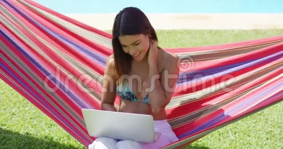 快乐的女人在吊床上用笔记本电脑视频的预览图