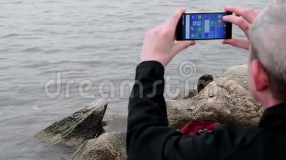 坐在湖岸上的中年老人孤独成熟的男人在银行拍摄视频孤独的概念视频的预览图