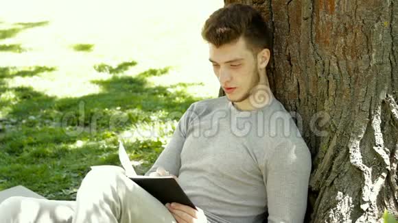 学生坐在公园的树荫下用记事本做笔记视频的预览图