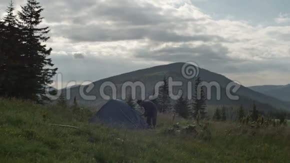 一个人从一个帐篷里出来这个帐篷安装在户外的树林里视频的预览图