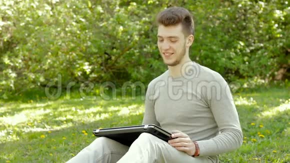 快乐的年轻人在公园打开一台笔记本电脑惊讶地笑了视频的预览图