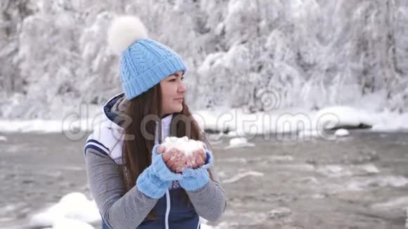 冬天河边的一个女人享受着一个寒冷的早晨把雪扔在自己身上从幸福中旋转视频的预览图