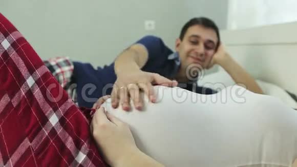 一个男人的手紧抚摸着一个孕妇的大肚子视频的预览图