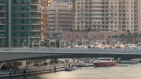 游艇和船只与游客停留在购物中心附近并通过桥下迪拜码头地区的时间推移视频的预览图