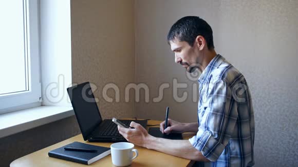 坐着笔记本电脑看手机的年轻人视频的预览图