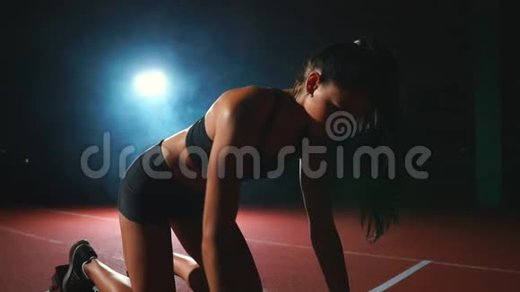 女运动员在黑暗的背景下在跑步机上跑越野跑的短跑视频的预览图