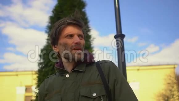 一位留着胡子的中年男子在一棵黄色针叶树的背景下目光转向远处与镜头交谈视频的预览图