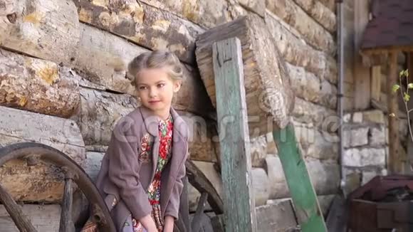 穿着传统服装站在老农村木屋前的小漂亮女孩的肖像全高清视频的预览图