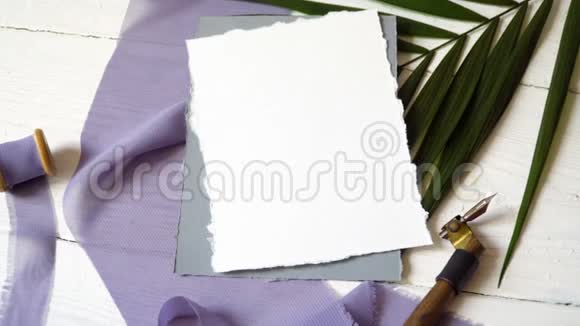 白色空白的贺卡丝带在蓝色织物的背景上棕榈叶和书法笔在白色上视频的预览图