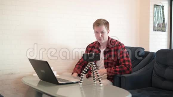 年轻英俊的时髦男人一边喝咖啡一边用笔记本电脑视频的预览图