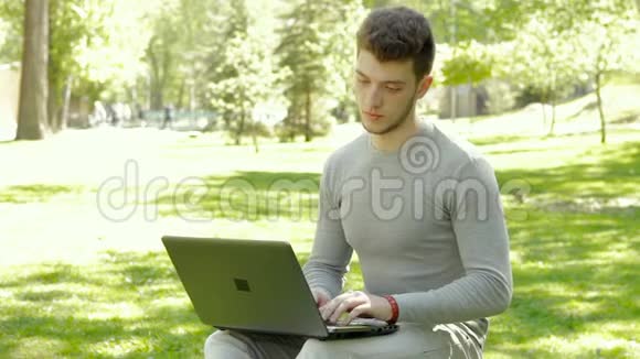 年轻学生在公园里用笔记本电脑学习视频的预览图