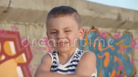 穿条纹衬衫的顽皮小孩背景墙上有涂鸦的可爱微笑视频的预览图