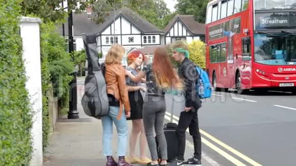四个暑假的年轻人提着手提箱吉他和背包站在汽车站附近视频的预览图