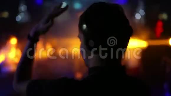 后景前台DJ的背面和耳机跳舞的人模糊了视频的预览图