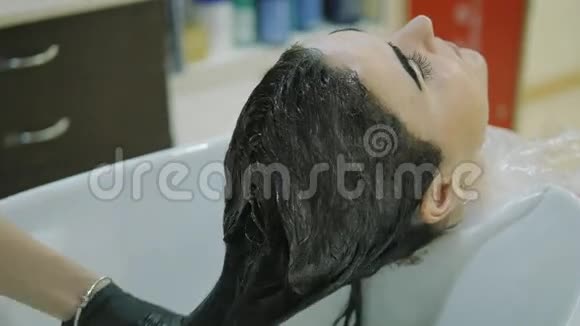 理发店头部侧视图女人用长长的黑发洗油漆漂亮的女孩用油漆涂在客户的脸上视频的预览图