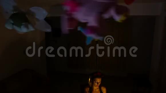 玩具在天花板下转动金发女郎在黑暗中的位置视频的预览图