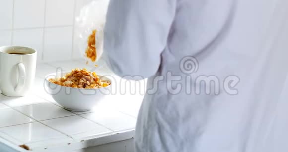 男人把早餐麦片倒进厨房的碗里视频的预览图