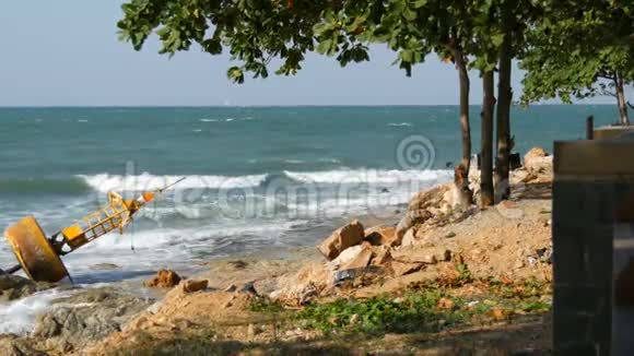 海景不错海浪拍打着石岸石岸上躺着废弃的黄色浮标有一棵树视频的预览图