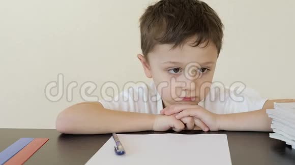 悲伤的小男孩坐在桌子旁做作业视频的预览图