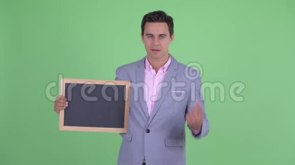 快乐的年轻英俊的商人拿着黑板竖起大拇指视频的预览图