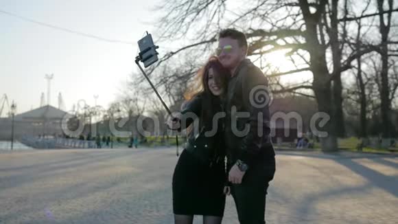 年轻情侣在背光手机在自粘网络交流时尚男女孩在公园散步视频的预览图