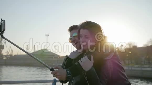 年轻人被拍到拥抱小玩意在自拍棒幸福夫妇的自拍照片男人手里的自拍照视频的预览图