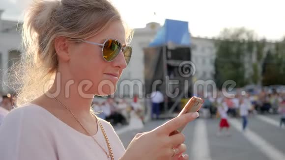 年轻女子手里拿着智能手机在街上微笑的女孩手里拿着手机在户外快乐的女性视频的预览图