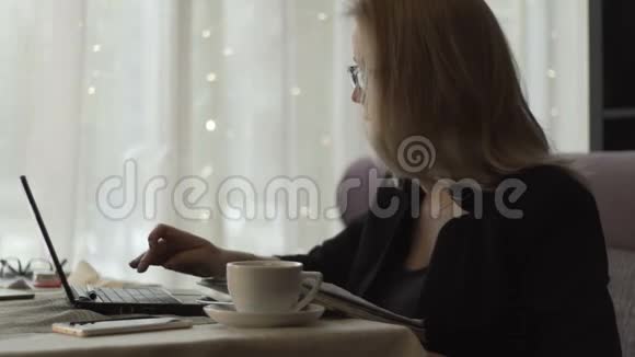 商务女性戴着眼镜在键盘上打字坐在咖啡馆的沙发上视频的预览图