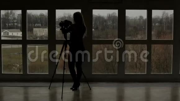 一个女摄影师靠在窗户上的剪影视频的预览图