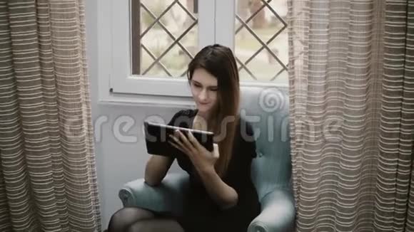 年轻漂亮的黑发女孩上网并使用平板电脑有魅力的女孩在家休息视频的预览图