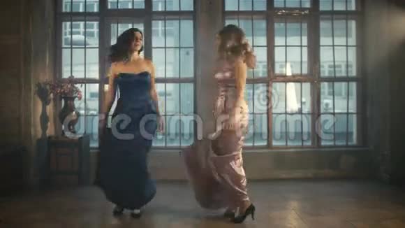 两个穿着晚礼服的漂亮女孩旋转着跳舞粉红色和蓝色的长裙很长一段时间金发女郎视频的预览图