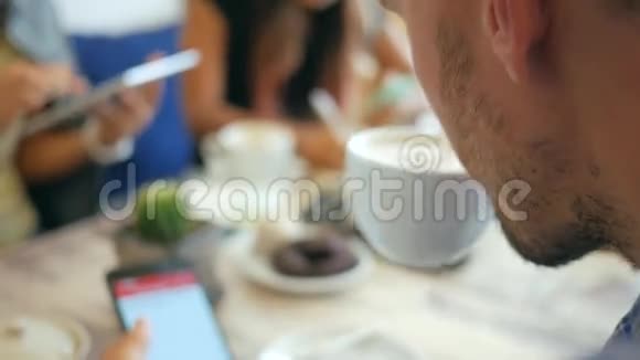 与移动小工具的朋友在咖啡厅年轻人喝咖啡和使用智能手机高清慢速生活方式特写视频的预览图