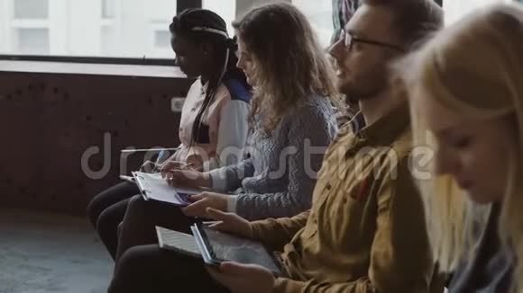 多种族团队坐在阁楼办公室听商业研讨会年轻的男人和女人用平板电脑做笔记视频的预览图
