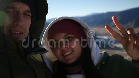 一对相爱的夫妇在山顶上自拍手指上有一个胜利的手势慢动作1920x1080视频的预览图