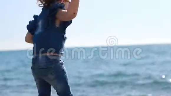 小女孩把石头从海岸扔进海水里视频的预览图