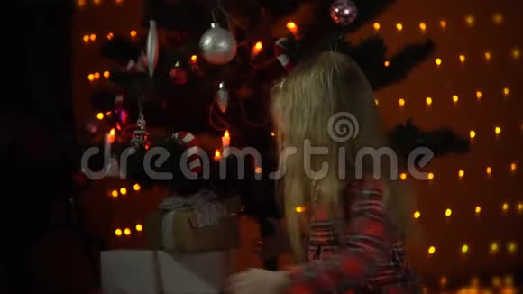 小女孩打开装饰圣诞树下的礼盒视频的预览图