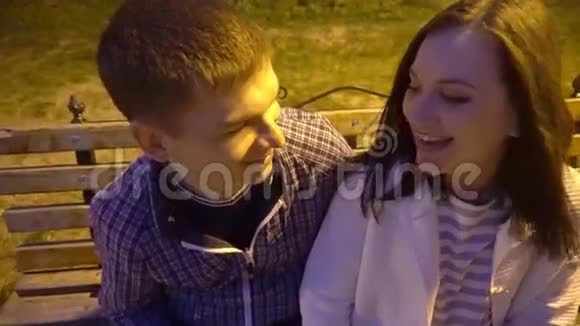 有吸引力的年轻夫妇在公园长凳上拥抱拥抱拥抱在爱情中快乐在他们20的男人和女人中视频的预览图