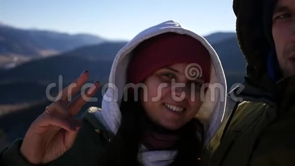 满意和快乐的男人和女人正在相机上拍一张照片站在山顶上戴着帽子慢动作视频的预览图