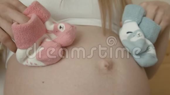 孕妇裸腹为未来新生男婴或女孩准备的袜子视频的预览图