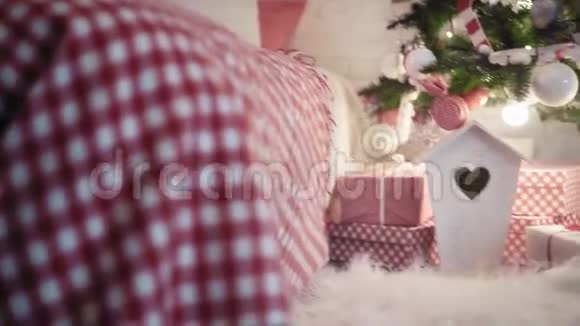 穿着红色高跟鞋的年轻漂亮女人把圣诞礼物放在圣诞树下近距离观看视频的预览图