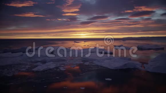 北极自然景观与冰山在格陵兰冰峡湾与午夜太阳日出的地平线空中无人机视频的预览图