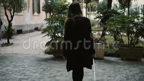 后景的年轻迷人的女人带着手提箱走在街上穿着黑色衣服的女性来到了新城市视频的预览图