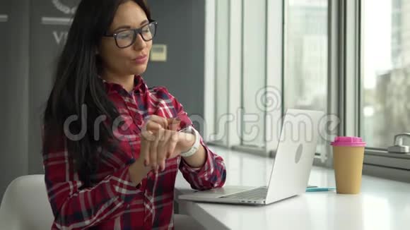 希普斯特混合种族妇女使用智能手表和笔记本电脑在咖啡馆工作视频的预览图