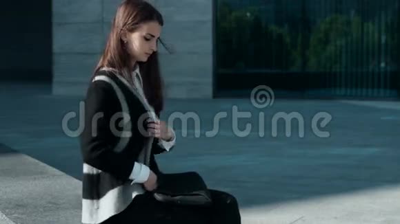 女孩坐在户外的风中与移动平板电脑合作视频的预览图