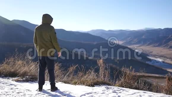 一个穿夹克衫的年轻人站在山顶上眺望远方从远处感受到自由和快乐视频的预览图