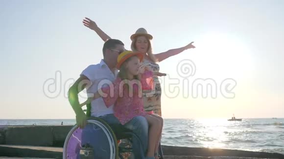 夏天无效一家人一起在背景蓝天上玩耍小女孩坐在轮椅上的爸爸视频的预览图