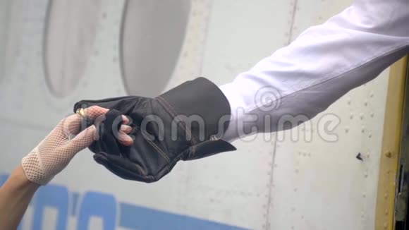 这个男人穿着复古服装的飞行员的手手里握着一个女人纤细的手手里拿着一只花边手套帮助一个人视频的预览图